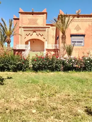 a house with a gate and palm trees in a yard at chez l'habitant amazigh in Ouarzazate