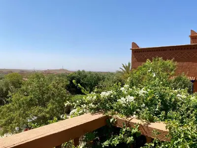 a garden with white flowers and a brick building at chez l'habitant amazigh in Ouarzazate