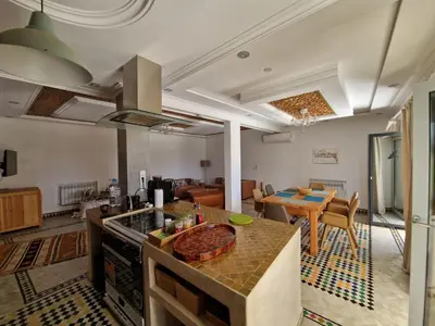 a kitchen and living room with a counter and a table at Villa Palmengarten Meknès bei Fes in Meknès