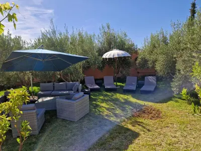 a group of chairs and an umbrella in a yard at Villa Palmengarten Meknès bei Fes in Meknès