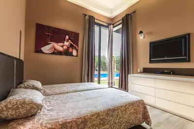 a bedroom with a bed and a flat screen tv at Villa 751, Villa d'architecte, cuisinière, piscine chauffée et services in Marrakech