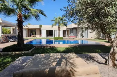 a house with a swimming pool and palm trees at Villa 751, Villa d'architecte, cuisinière, piscine chauffée et services in Marrakech