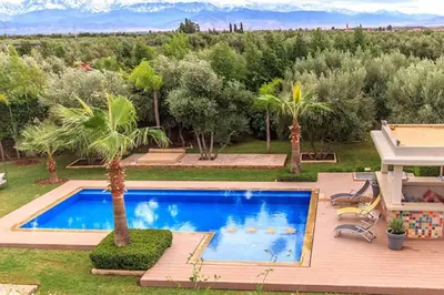 a swimming pool in a yard with palm trees at Villa 751, Villa d'architecte, cuisinière, piscine chauffée et services in Marrakech