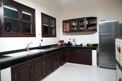 a kitchen with wooden cabinets and a stainless steel refrigerator at Villa Tifira in Marrakech