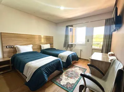 a hotel room with two beds and a chair at AUBERGE JOMANA PARK in Azrou