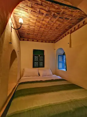a bed in a room with a wooden ceiling at Kasbah Ziwana - Guesthouse in Zagora