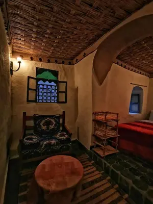 a room with a bed and a chair and a window at Kasbah Ziwana - Guesthouse in Zagora