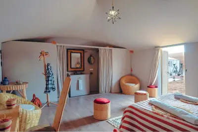 a room with a bed and wicker chairs in it at Aisha Luxury Camp in Merzouga