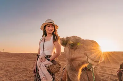 a woman standing next to a camel in the desert at Aisha Luxury Camp in Merzouga