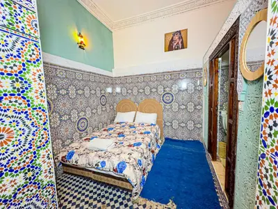 a bedroom with a bed and a blue carpet at Hostel Speakeasy Fes in Fès