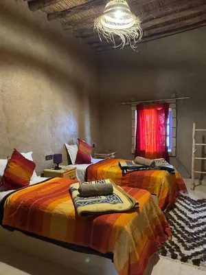 a bedroom with two beds and a chandelier at Auberge Camping La Libertè in Merzouga