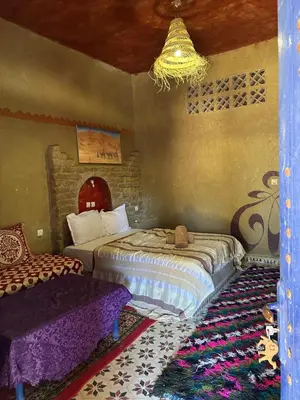 a bedroom with two beds and a chandelier at Auberge Camping La Libertè in Merzouga