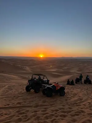 a group of people sitting in the desert with atvs at Auberge Camping La Libertè in Merzouga