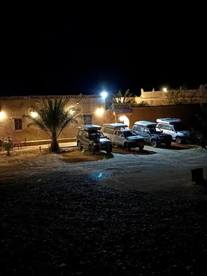 a group of cars parked in a parking lot at night at Auberge Camping La Libertè in Merzouga
