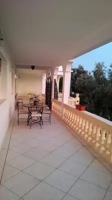 a porch with benches and tables on a house at Domaine des Sloughis in Meknès