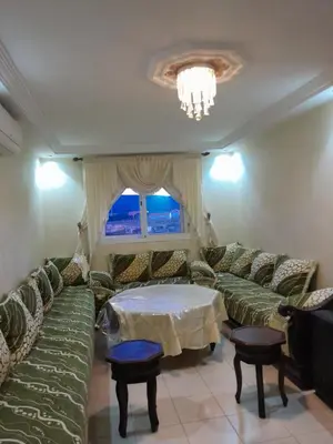 a living room with green couches and a table at Marwan's apartment Ifrane Gardens in Ifrane