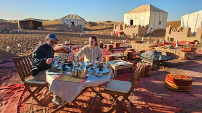 a man and a woman sitting at a table in the desert at Nejma luxury camp erg chegaga in El Gouera