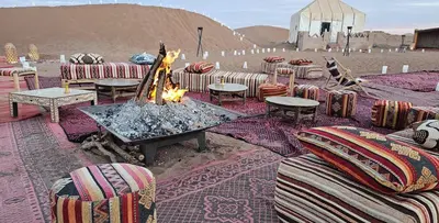 a fire pit with chairs and tables in the desert at Nejma luxury camp erg chegaga in El Gouera