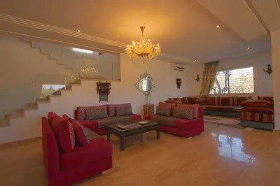 a living room with red couches and a chandelier at Villa Meriem, Fès in Oulad Tayeb