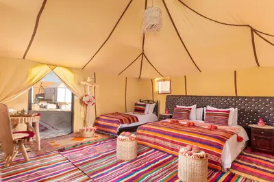 a bedroom with two beds in a tent at Alibaba Merzouga Camp in Merzouga