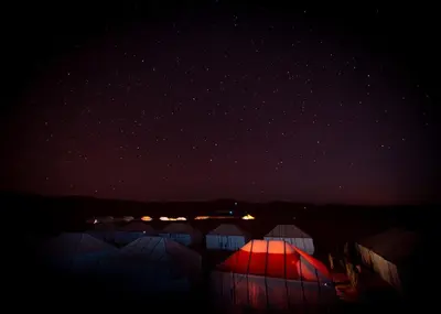a starry night with a red light in the sky at Alibaba Merzouga Camp in Merzouga
