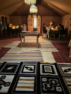 a room with a table and people sitting at tables at Morocco Desert Luxury Camp in Merzouga