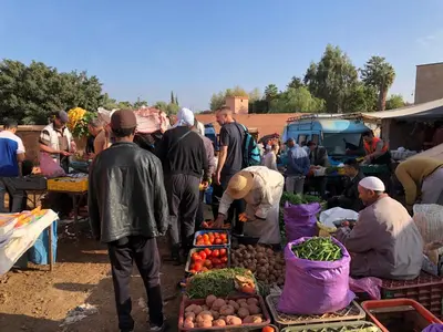 a group of people standing around a market with produce at Guest House Tigminou in Setti Fatma