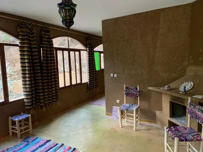 a living room with two chairs and a fireplace at Guest House Tigminou in Setti Fatma