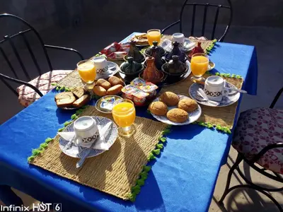 a blue table with breakfast foods and orange juice at Sahara camel tours camp in Merzouga