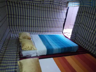 a small bed in a room with a window at Sahara camel tours camp in Merzouga
