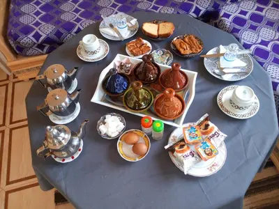 a table with a blue table cloth with food and tea at Sahara camel tours camp in Merzouga