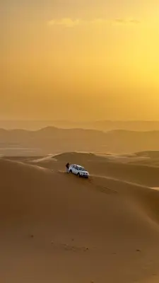 a car driving through the sand in the desert at Royal Sands Camp in Merzouga