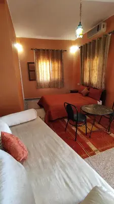 a hotel room with two beds and a table at Hotel camping le Soleil Tinghir in Tinerhir