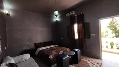 a bedroom with a bed and a couch and a window at Hotel camping le Soleil Tinghir in Tinerhir