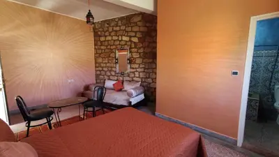 a bedroom with a bed and a table and a couch at Hotel camping le Soleil Tinghir in Tinerhir