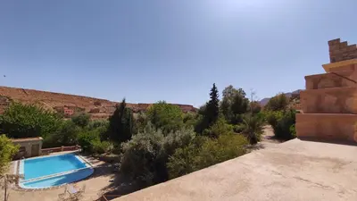 a swimming pool in the middle of a desert with trees at Hotel camping le Soleil Tinghir in Tinerhir