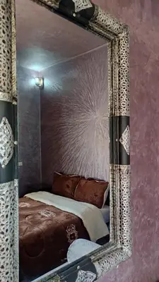 a mirror reflecting a bed in a room at Hotel camping le Soleil Tinghir in Tinerhir