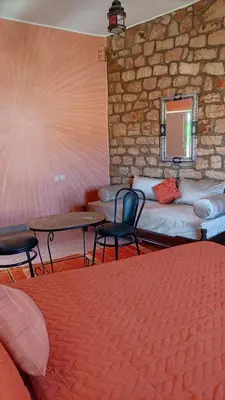 a room with two beds and a table and chairs at Hotel camping le Soleil Tinghir in Tinerhir