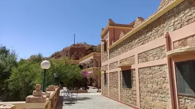 a building with a stone wall and a courtyard at Hotel camping le Soleil Tinghir in Tinerhir