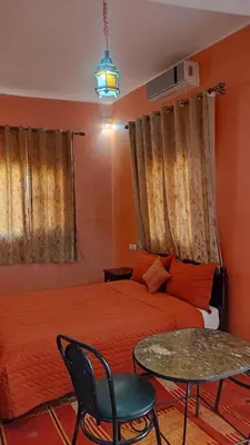 a bedroom with a bed and a table and chairs at Hotel camping le Soleil Tinghir in Tinerhir