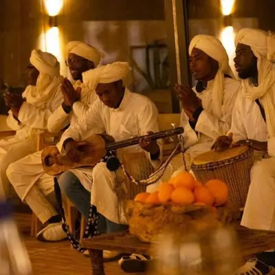 a group of men dressed in white holding a gun at Sahara Nights Luxury Camp in Merzouga