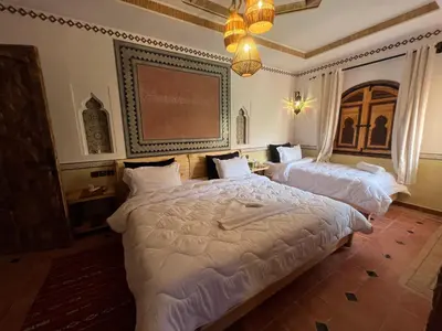 a bedroom with two beds and a chandelier at Grand Canyon Lodge Dades in Aït Idaïr