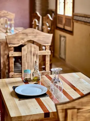 a wooden table with a plate and glasses on it at Grand Canyon Lodge Dades in Aït Idaïr