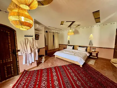 a bedroom with a bed and a red rug at Grand Canyon Lodge Dades in Aït Idaïr