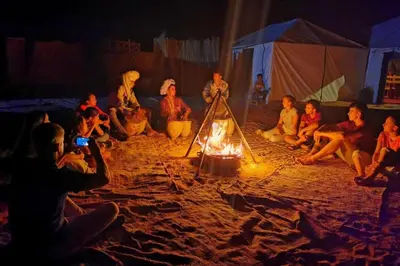 a group of people sitting around a fire at Bright Star Desert Camp in Merzouga