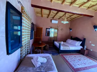 a bedroom with two beds and a tv in a room at Maison d'hôtes imouzzar asfalou in Aït Ben Haddou