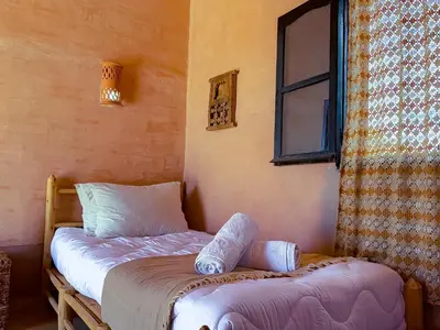 a bedroom with two twin beds and a window at Maison d'hôtes imouzzar asfalou in Aït Ben Haddou