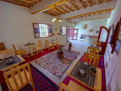 a living room with a table and chairs and a rug at Maison d'hôtes imouzzar asfalou in Aït Ben Haddou
