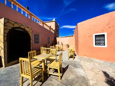 a group of wooden tables and chairs outside a building at Maison d'hôtes imouzzar asfalou in Aït Ben Haddou