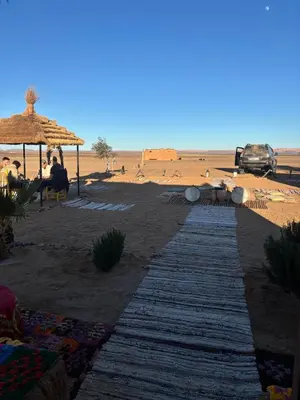 a path on a beach with an umbrella and people at Camp Desert Sky in Merzouga